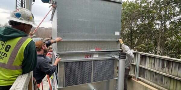 Young's Mechanical technician rigging a commercial rooftop packaged HVAC unit — rooftop, RTU