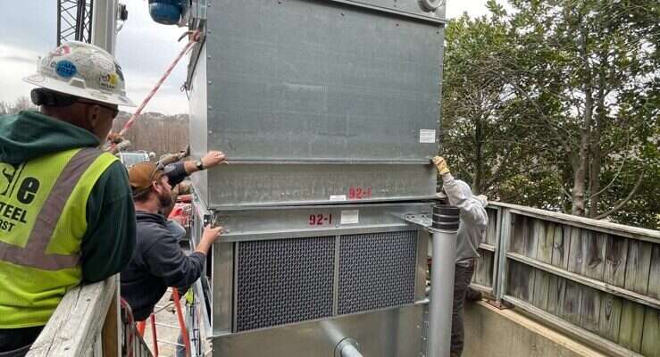 Young's Mechanical technician rigging a commercial rooftop packaged HVAC unit — rooftop, RTU