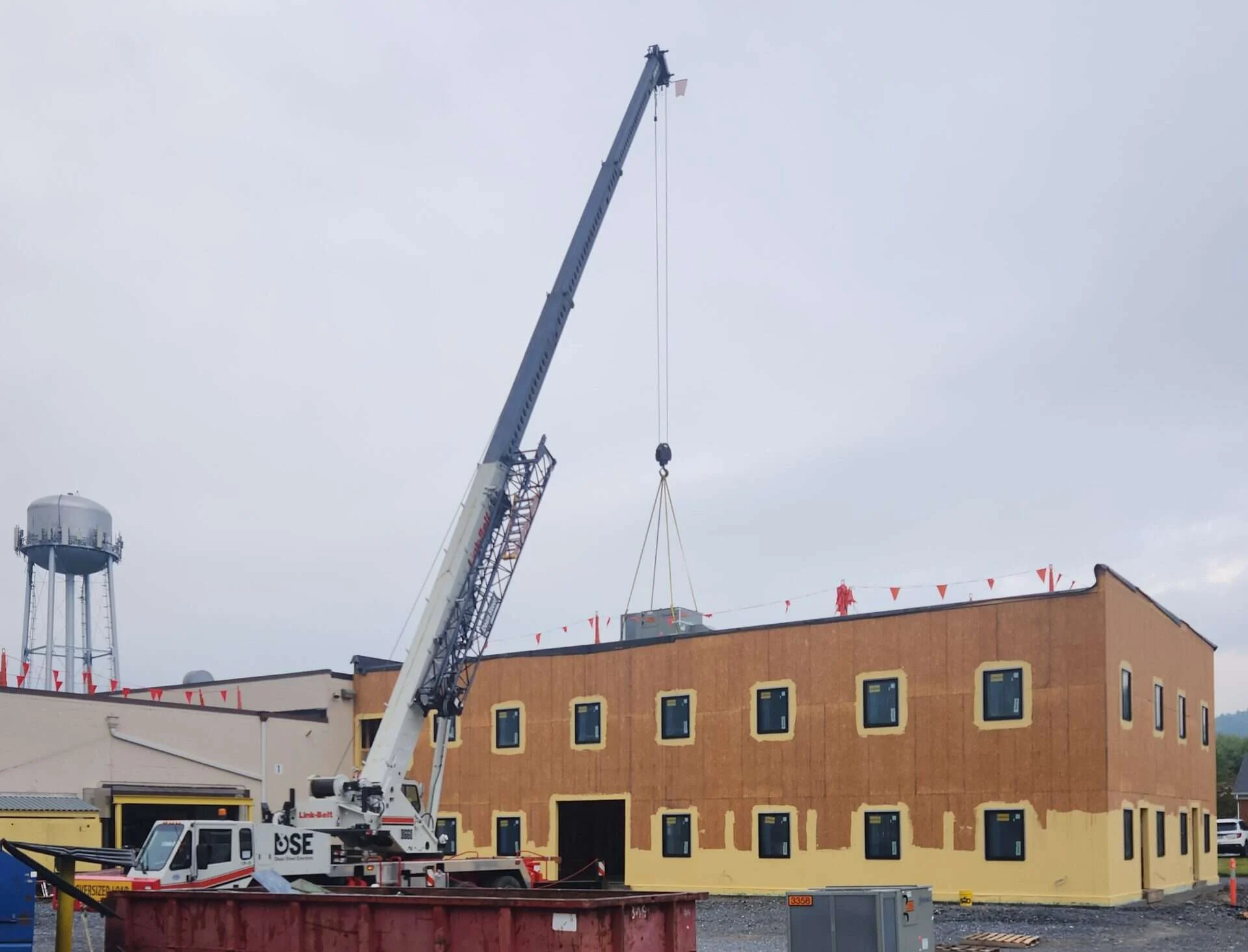 Crane hoisting a packaged rooftop HVAC unit onto the roof of the Shickel Corporation office addition in Bridgewater, Virginia