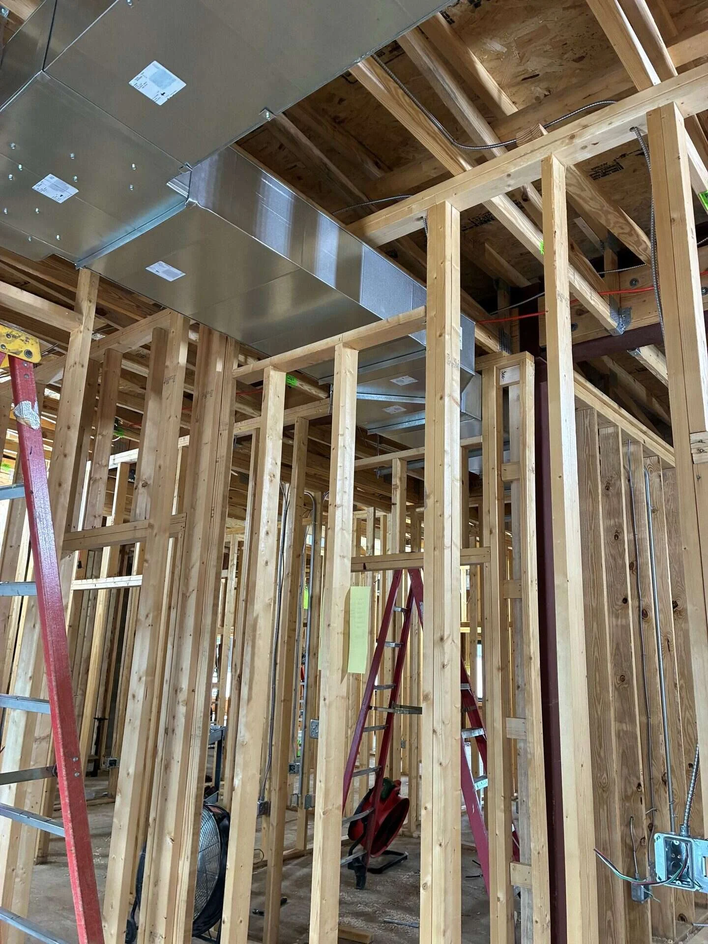 Galvanized sheet metal supply trunk and branch ducts installed above wood framing on a commercial construction site
