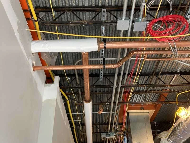 Insulated and copper domestic water piping run overhead in a commercial building, installed by Young's Mechanical Solutions