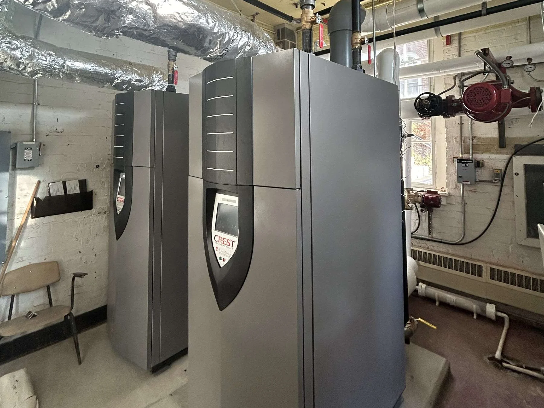 Two commercial condensing boilers in a mechanical room installed by Young's Mechanical Solutions